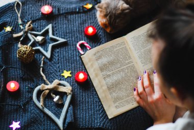 Kız güzel arka kedi garland arka planı olan bir kitap okuma