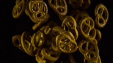 Simit tuz ile yükselen. Fırında kraker kamera önünde gezinip karanlıktan ortaya ve gölgelerin içinde kaybolur. Ağır çekim 240 fps hızında