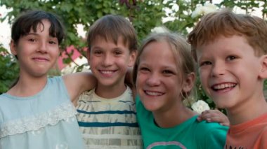 Neşeli Cmpany arkadaş. Sarılma ve birlikte gülüyor dört arkadaş ağaçlar arka plan üzerinde eğleniyor. 240 fps hızında filme