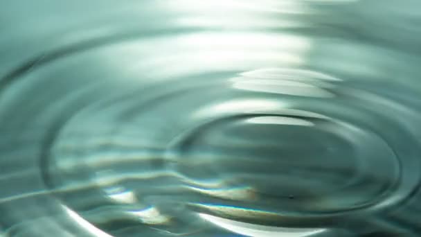Chute des gouttes transparentes. Une goutte de liquide tombe lentement à la surface de l'eau. Une belle éclaboussure et des cercles sur l'eau. Filmé à une vitesse de 240 images par seconde 