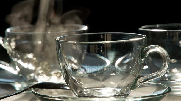 我们三的茶叶 一股热水从水壶里倒入一个透明的茶杯里 站在背景中 在前景立场空的透明杯子 以240Fps 的速度拍摄 — 图库视频影像