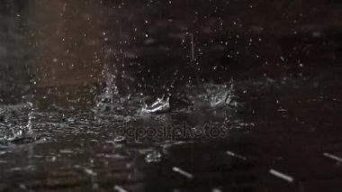 Yağmur damlaları kaldırımda düşmek. Yağmur damlaları Çatı döşeme plağını parke granit üzerine düşer. 240 fps hızında filme