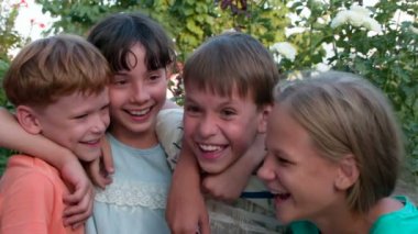 Dört gülen çocuk. Sarılma ve birlikte gülüyor dört arkadaş ağaçlar arka plan üzerinde eğleniyor. 240 fps hızında filme