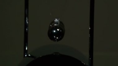 Çelik Top Sallama Hareketi. Döngü. Çelik gibi parlak toplar arka planda asılı duruyor. Birbirleriyle etkileşime girerek çarpışma kuvvetini aktarıyorlar. 240 fps hızla çekiliyor.