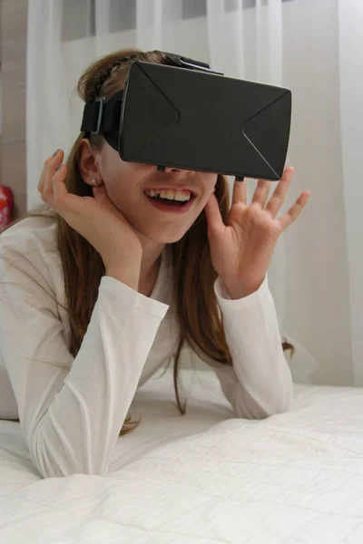 Girl in Virtual Reality headset looking up and trying to touch o