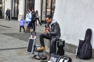 Krakov/Polonya - 6 Ocak 2018: içinde Krakow kare bir sokak müzisyeni gitar çalıyor. O çeşitli işleri gerçekleştirir ve yoldan geçenler tarafından dinledi