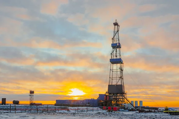Kuzey tundrada petrol ve gaz sondaj kulesi. Kuzey Kutbu 'nda kış. Kutup gününün güneşi bulutların arasında parıldıyor. Arka ışıklandırma.