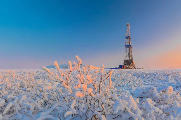Kışın karla kaplı tundrada petrol ve gaz sahasında bir kuyu kazılıyor. Kutup günü. Güzel gökyüzü. Sondaj kulesi karla kaplı..