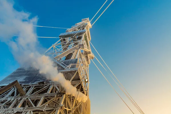 Kışın kuzey petrol ve gaz sahasında sondaj. Platform karla kaplı ve kutup gününde güneş tarafından aydınlatılıyor. Teçhizatı ısıtmak için buhar girdabı.