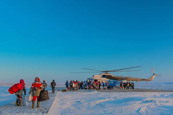 Kuzey Tundra 'daki ahşap helikopter pistinde bir kutup havacılık helikopteri, sondaj kuyusundan çok uzak değil. Matkapçılar ve petrol işçileri adanmış ve ekipmanlar yükleniyor. Kış kutup günü.