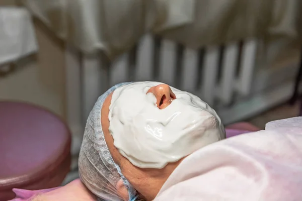 Cosmetic procedure with laying alginate masks on the face in a beauty salon. It is performed for an age woman. Improving skin turgor, rejuvenation and healing.