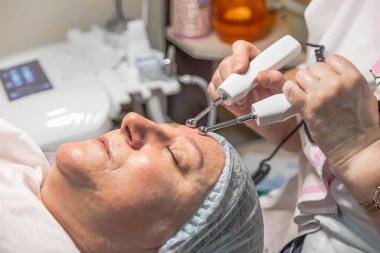 Güzellik salonunda mikro akım enjeksiyonlarıyla yapılan kozmetik bir işlem yaşlı bir kadın için yapılır. Deri turgor, yenilenme ve iyileşme.