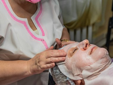 Güzellik salonunda zararsız yüz karboks terapisi. Yaşlı bir kadın için yapılıyor. Derinin altına karbondioksit enjekte edilmemiş transdermal yönetim. Yüzünde maske.