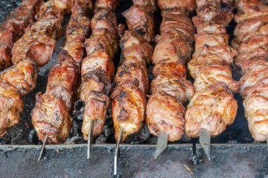 Kömürde barbekü yapmak. Metal şişler üzerine dizilmiş pembe et parçaları. Kanserojen içeren zararlı ve zararlı yiyecekler.