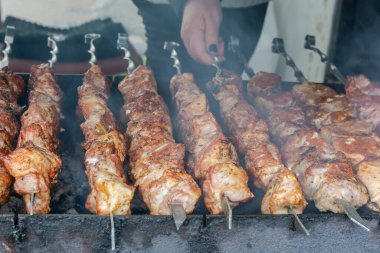 Kömürde barbekü yapmak. Metal şişler üzerine dizilmiş pembe et parçaları. Kanserojen içeren zararlı ve zararlı yiyecekler.