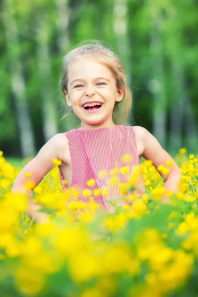 Glad liten tjej på blommande äng — Stockfoto