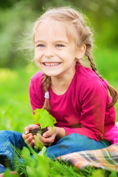 Little girl gazdaság kis zöld növény a kezében — Stock Fotó