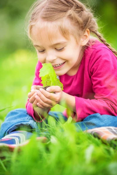 Küçük kız küçük yeşil bitki onun elinde tutan — Stok fotoğraf