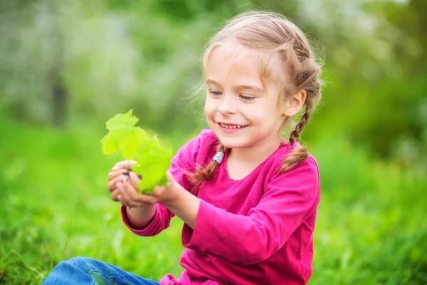 她手里拿着一些绿色植物的小女孩 — 图库照片