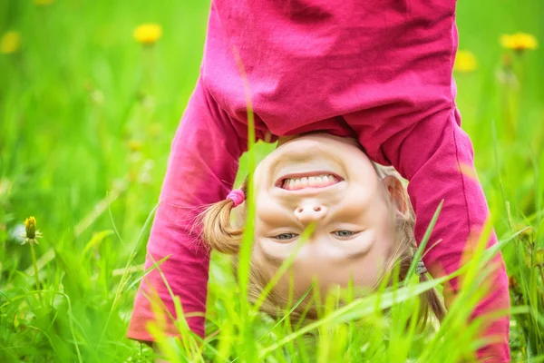 Boldog kislány állt fejjel lefelé a fű a nyári park — Stock Fotó
