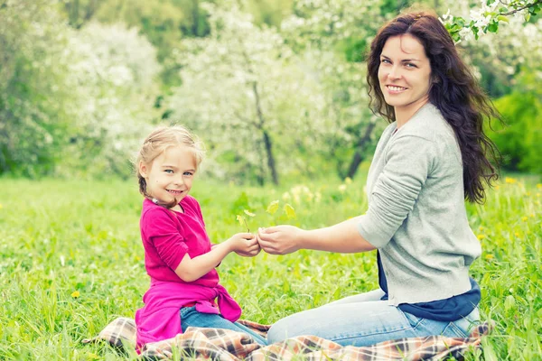 Madre e hija sosteniendo una pequeña planta verde en las manos —  Fotos de Stock