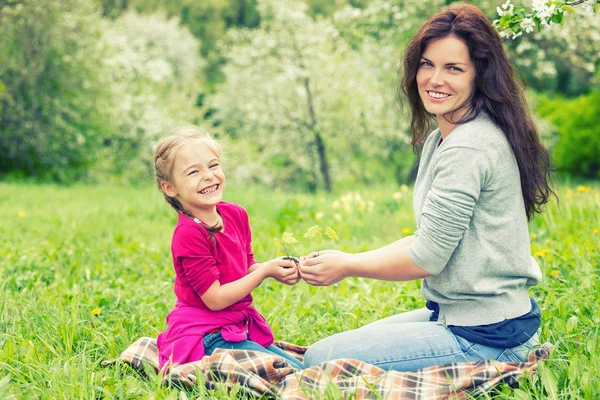 Madre e hija sosteniendo una pequeña planta verde en las manos —  Fotos de Stock