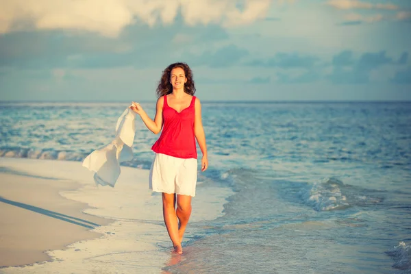 Genç bir kadın sahilde yürüyor. — Stok fotoğraf