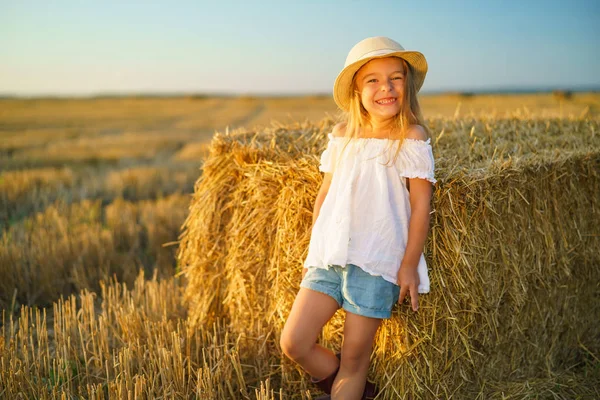 Niña en un campo con rollos de heno — Foto de Stock