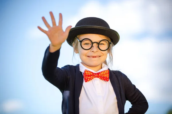 Muchacha divertida en corbata de lazo y sombrero de jugador de bolos con gesto de hola . — Foto de Stock