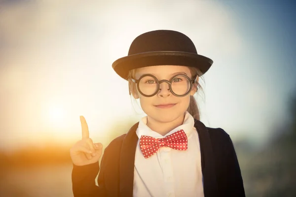 Funny little girl in glasses, bow tie and bowler hat. — Stock Photo, Image