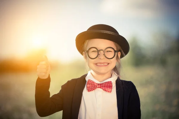 Lustiges kleines Mädchen in Fliege und Melone zeigt Daumen hoch. — Stockfoto