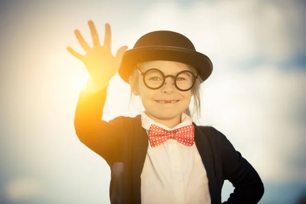 Lustiges kleines Mädchen in Fliege und Melone mit Hallo-Geste. — Stockfoto