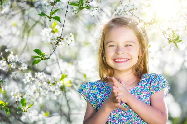 Lycklig liten flicka i körsbärsblom trädgård — Stockfoto