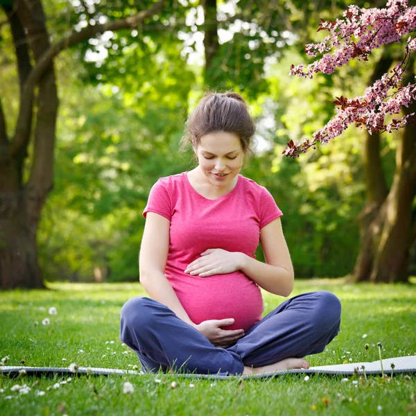 Έγκυος γυναίκα χαλαρώνοντας στο πάρκο άνοιξη — Φωτογραφία Αρχείου