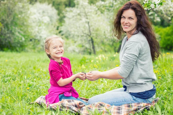 Mother and daughter holding little green plant in hands — Stock Photo, Image