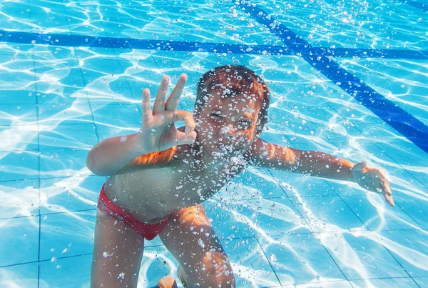 Garçon nager dans la piscine derrière les bulles d'air — Photo
