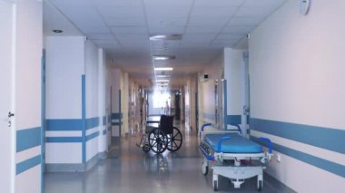 Hastane koridorunda tekerlekli sandalye ve sedye var..