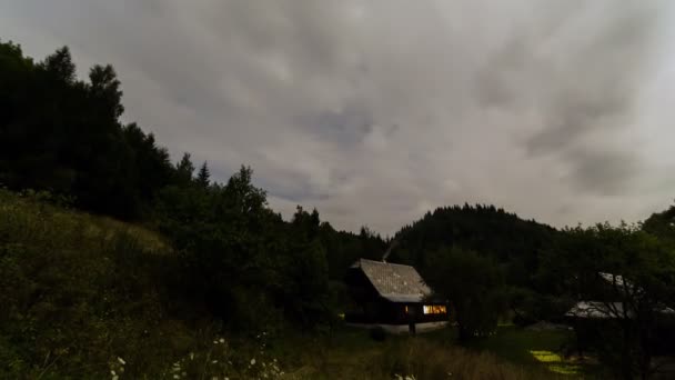 Nubes moviéndose sobre la cabaña por la noche caducan. Noche romántica en cabaña de madera — Vídeos de Stock