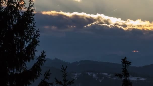 Сонце піднімається над хмарами і лісовим пейзажем в зимовий час. Драматичний ранок з деревами, що рухаються у вітрі — стокове відео