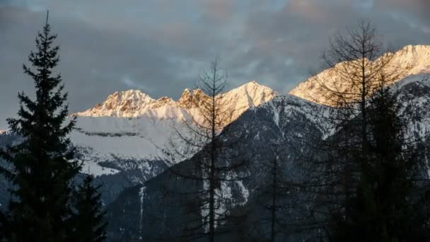 Colores de la tarde del atardecer sobre los Alpes nevados Montañas Time Lapse. Dolly disparó sobre árboles — Vídeos de Stock