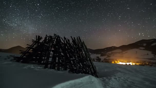Nocne niebo z gwiazdami przesuwania po zimie wiejskich kraju z drewnianej ramy, upływ czasu astronomii, dolly strzał nad śnieg — Wideo stockowe