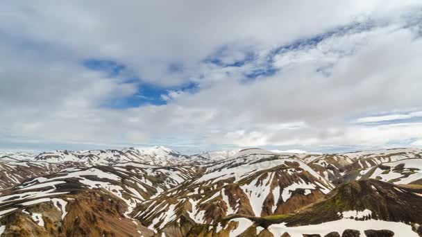 Mraky táhnou nad zasněženou duhové hory Islandu v Landmannalaugar. Panoramatické časová prodleva