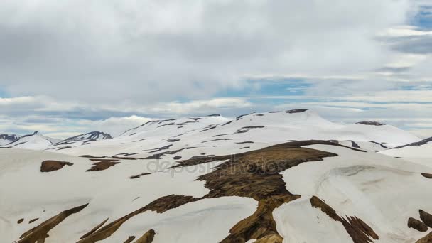 Mraky táhnou nad zasněženou duhové hory Islandu v Landmannalaugar. Time lapse otáčení