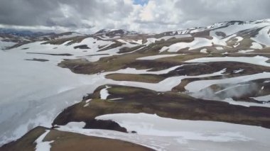 İzlanda'daki karlı volkanik dağlar üzerinde dramatik bulutların havadan görünümü