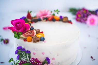 Beyaz ahşap arka planda taze meyve ve gül çiçekli tatlı beyaz peynirli turta. Doğum günü, isim günü, sevgililer günü ve kutlama için ideal bir hediye..