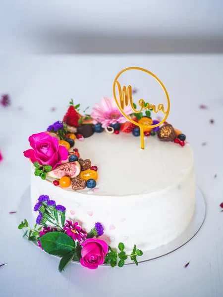 Beyaz ahşap arka planda taze meyve ve gül çiçekli tatlı beyaz peynirli turta. Annemin doğum günü, isim günü ve kutlama için ideal bir hediye..