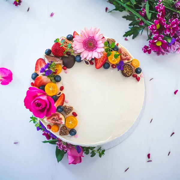 Beyaz ahşap arka planda taze meyve ve gül çiçekli tatlı beyaz peynirli turta. Doğum günü, isim günü, sevgililer günü ve kutlama için ideal bir hediye..