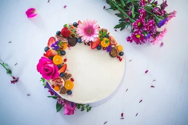 Beyaz ahşap arka planda taze meyve ve gül çiçekli tatlı beyaz peynirli turta. Doğum günü, isim günü, sevgililer günü ve kutlama için ideal bir hediye..