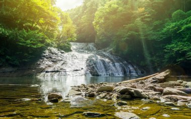 Japan travel concept - beautiful yoro keikoku valley waterfall under dramatic sun glow and morning blue sky in Chiba Prefecture, Japan clipart