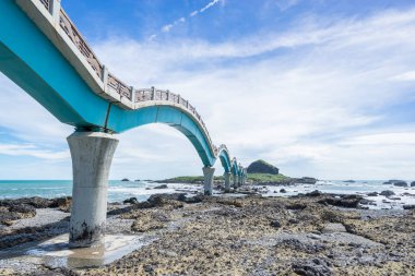 Panoramik Sansiantai Köprüsü ile güzel deniz seviyesi ve resif kayaları Sansiantai Taitung fantezi mavi bulutlu ve güneşli gökyüzü altında. Tayvan ünlü konumlar.
